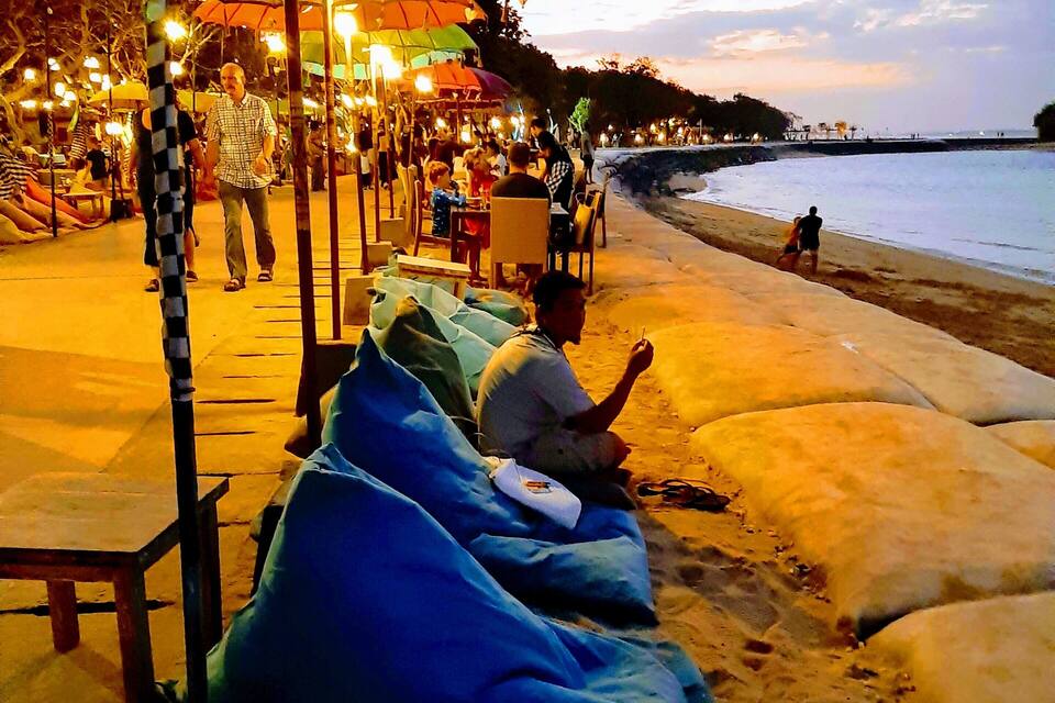 A beachside café with outdoor seating and umbrellas.