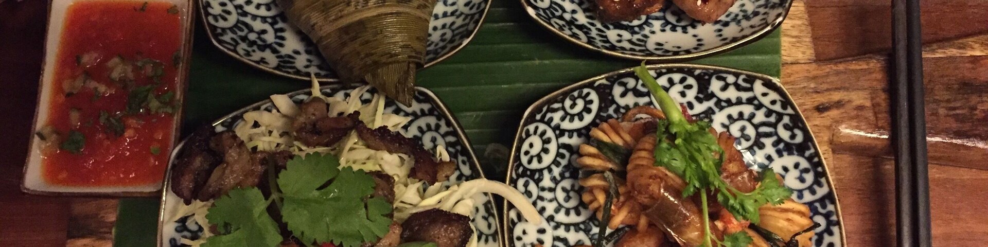 Uma mesa com quatro pratos de comida, incluindo um tamal, frango grelhado, legumes salteados e um prato com arroz e carne.