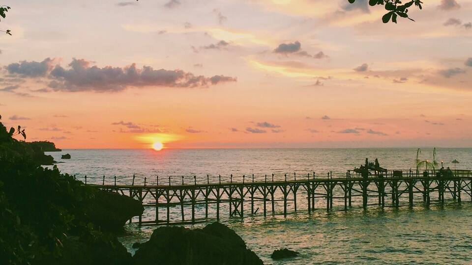 A sunset over the ocean with a pier extending into the water.