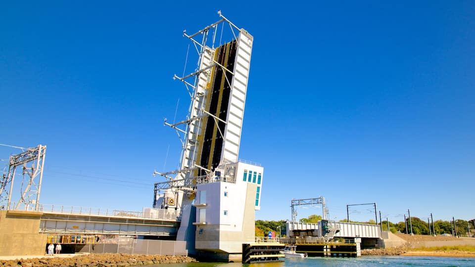 A large industrial structure with a tall tower, a bridge, and a body of water.