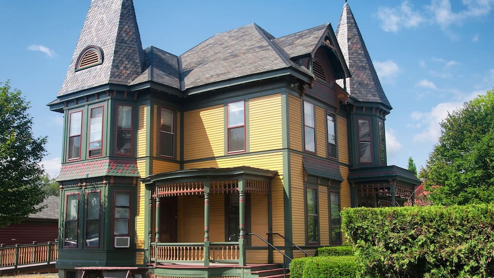 A Victorian-style house with green trim and two prominent towers.