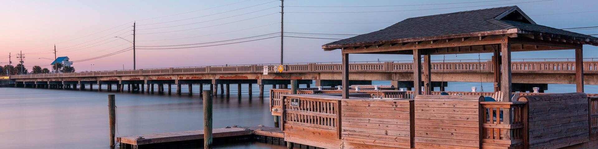 The sun is setting and sky is almost clear of clouds at this Private dock in the Banks Channel near River To The Sea Bikeway bridge in Wrightsville Beach, North Carolina