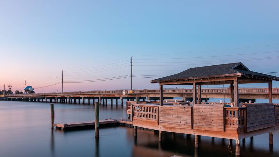 The sun is setting and sky is almost clear of clouds at this Private dock in the Banks Channel near River To The Sea Bikeway bridge in Wrightsville Beach, North Carolina