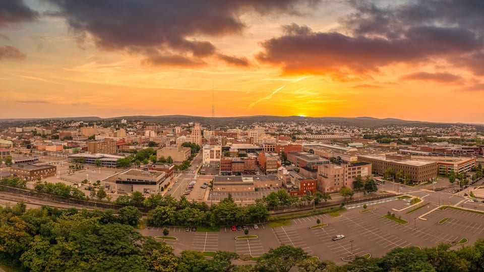 A cityscape at sunset with a prominent building and a parking lot.