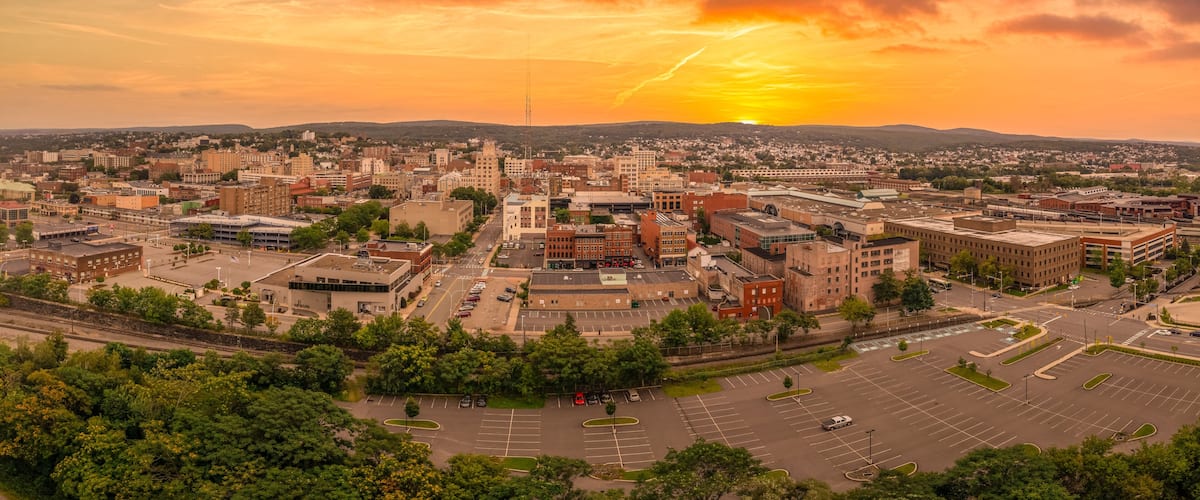 A cityscape at sunset with a prominent building and a parking lot.
