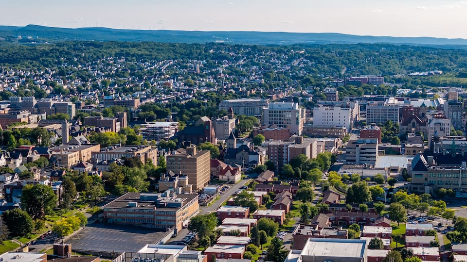 A densely populated urban area with a mix of residential and commercial buildings, surrounded by green hills.