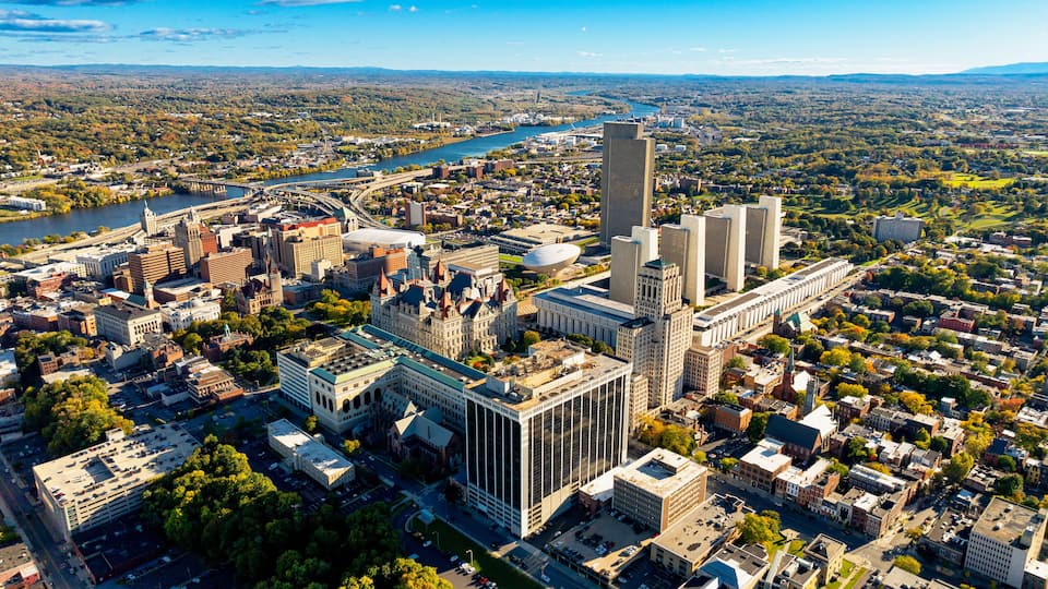Albany cityscape and river view. A stunning aerial perspective of Albany, USA reveals the vibrant cityscape, river, and surrounding greenery on a clear day.