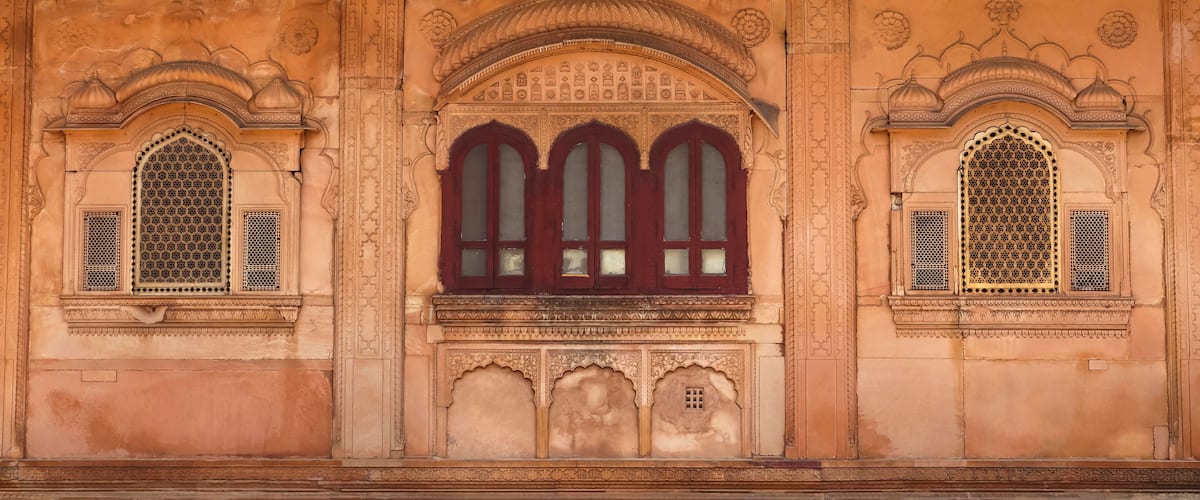 A building with intricate carvings and three arched windows with red frames.