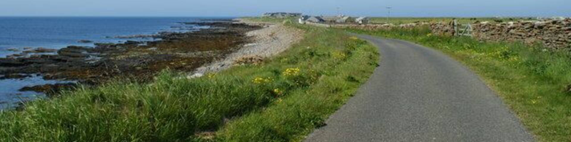 Road alongside Bay of Sandquoy Road runs alongside the eastern shore of the Bay of Sandquoy , only just above the high tide level on the island of Sanday.