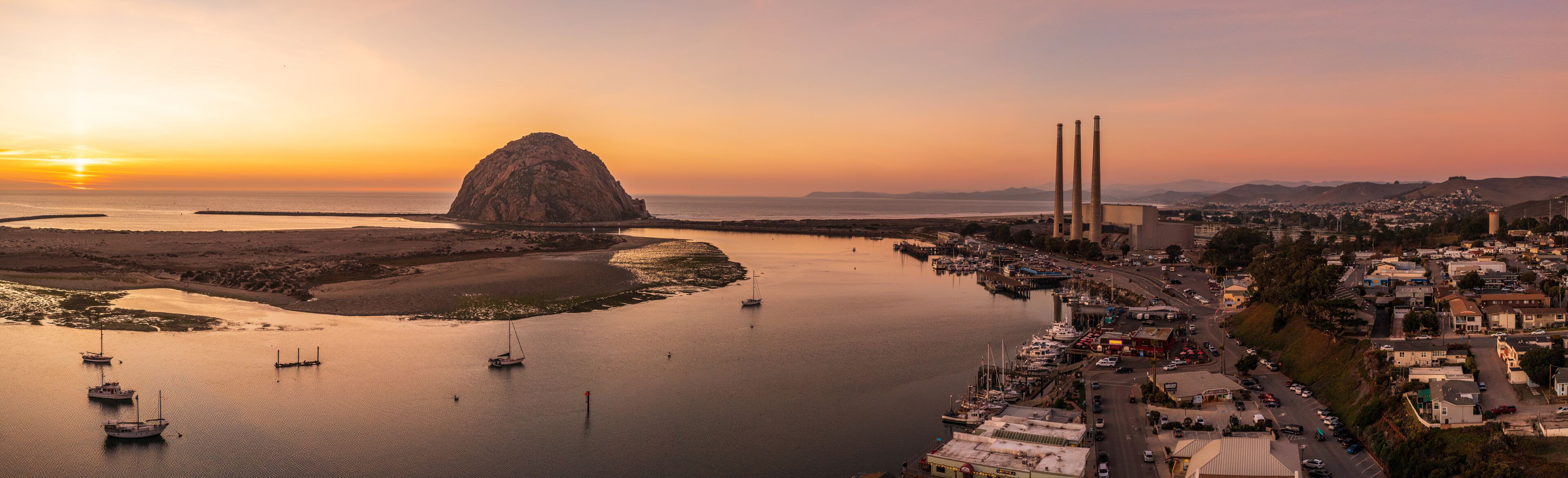 Aerial panorama of Morro Bay rock at sunset.