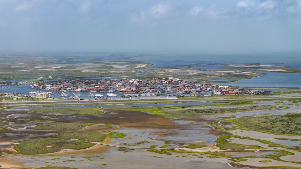 Port Aransas, USA, aerial landscape view of Mustang Beach Airport with Mustang Beach residential area located on Mustang Island at Gulf of Mexico with Corpus Christus Bay in background
