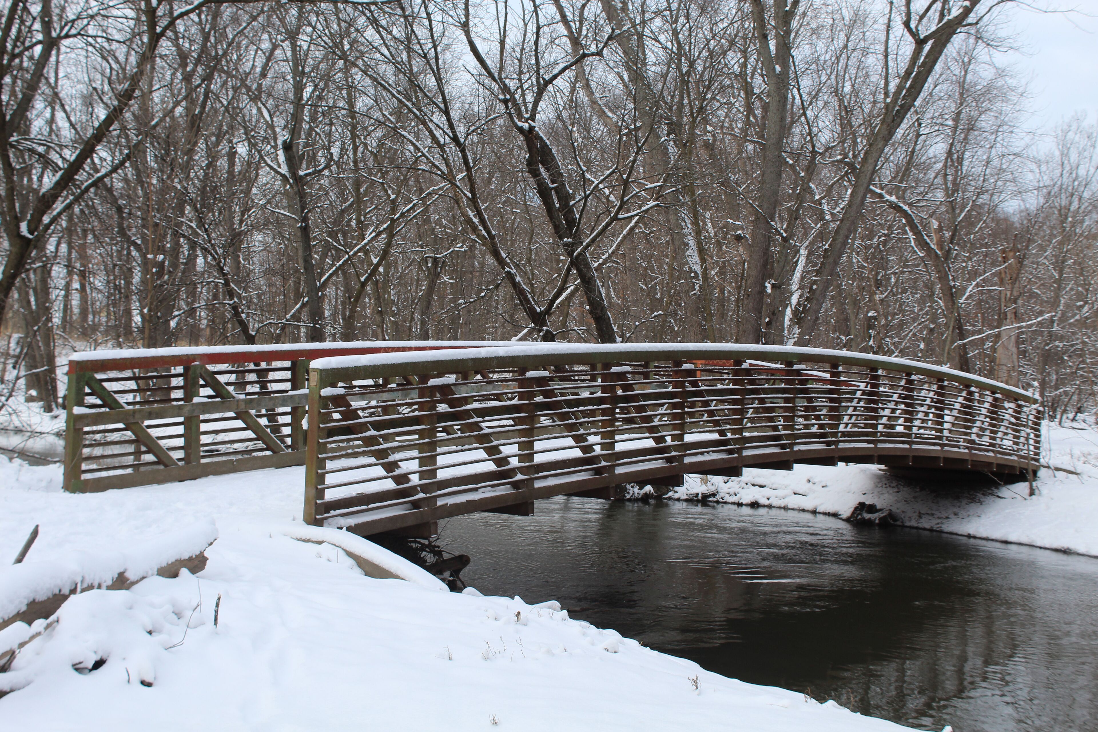 Footbridge in winter with snow over the North Branch of the Chicago River at Linne Woods in Morton Grove, Illinois