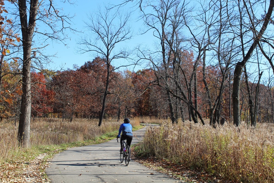 Man riding a bicycle in fall on a sunny day at Miami Woods on the North Branch Trail in Morton Grove, Illinois