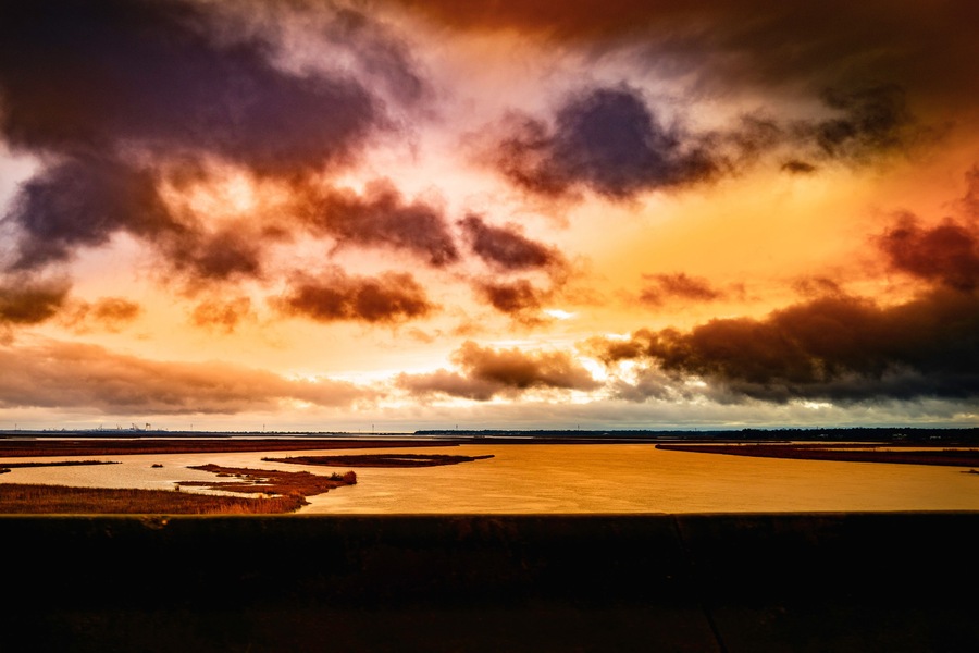 Dramatic winter weather conditions and cloudscape at sunrise over the Pascagoula River near Creole Bayou, Mississippi, USA, saturated road trip snapshot