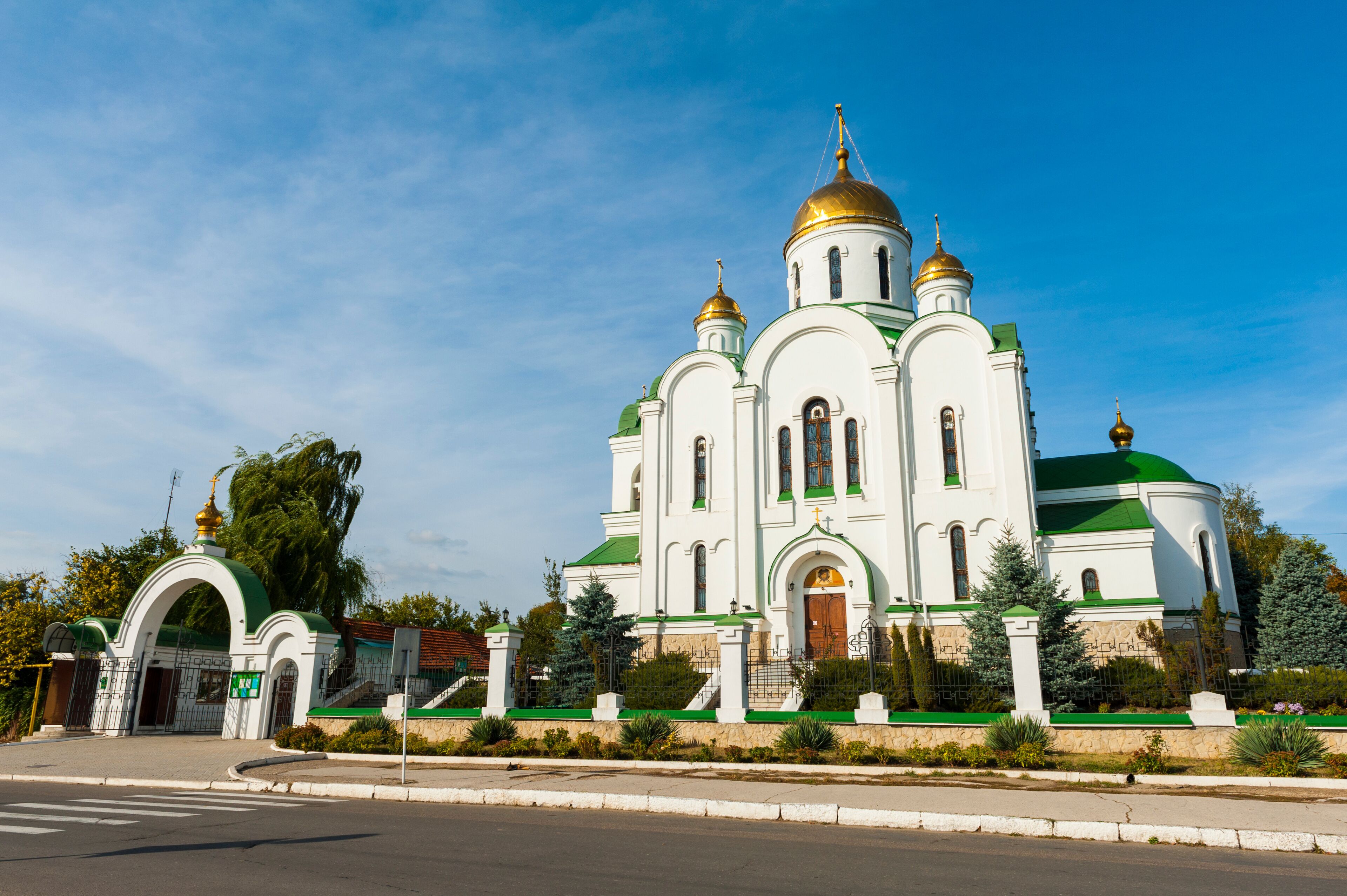 A white church with green domes and gold accents.