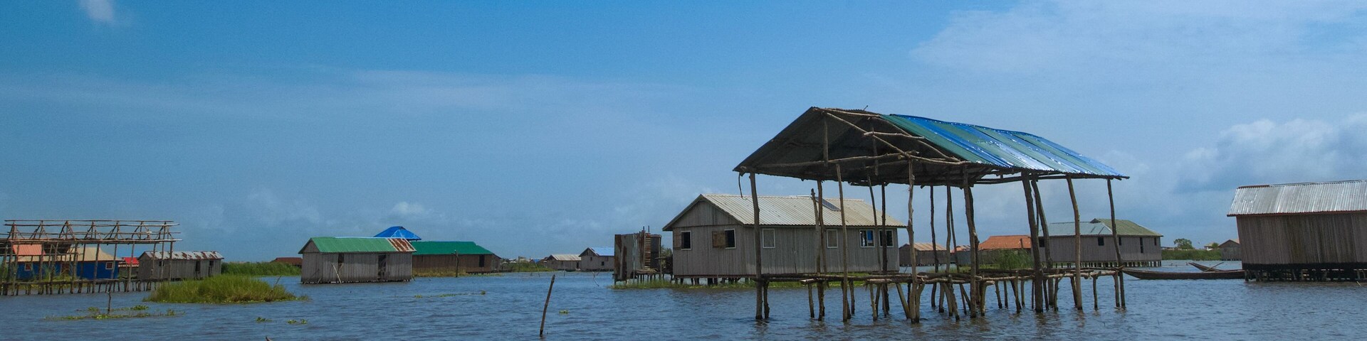 A floating village with wooden houses and a thatched roof structure.