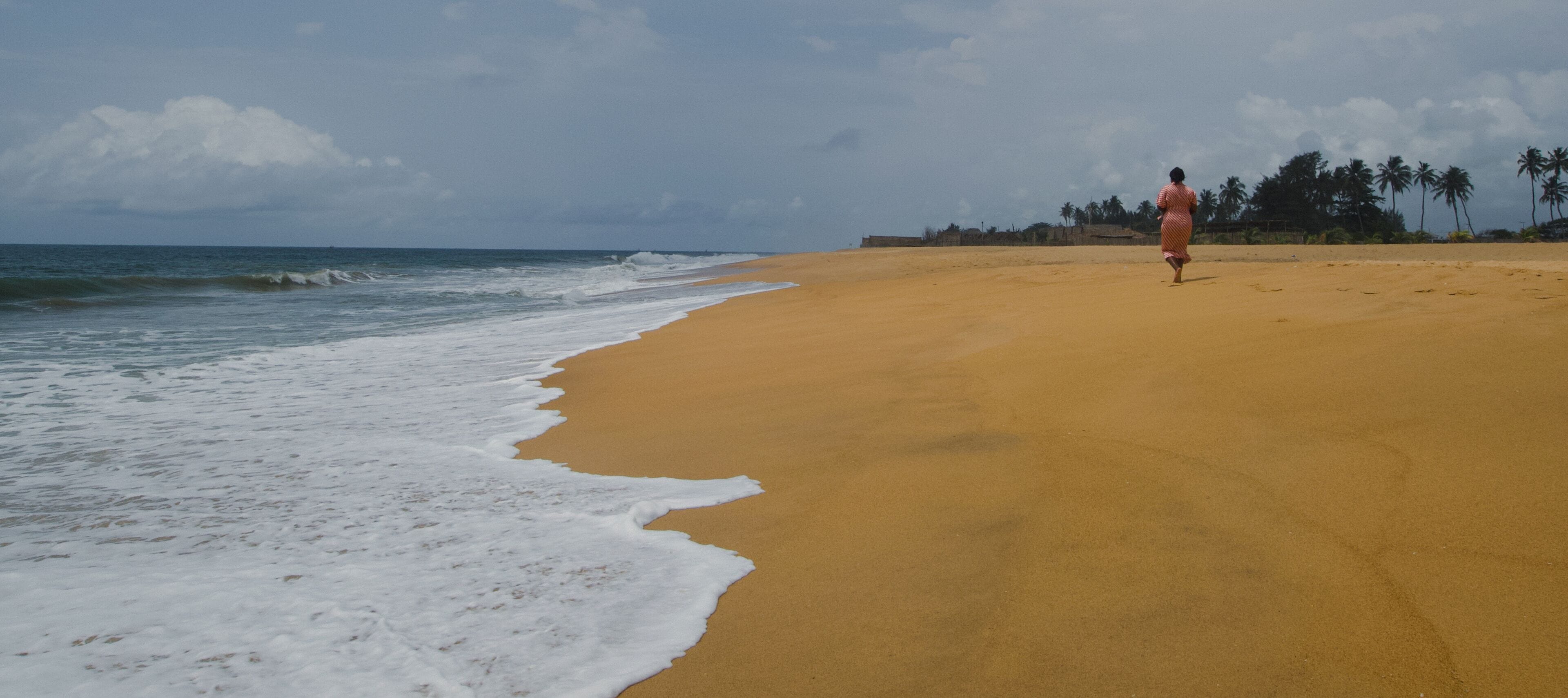 Beninese woman walking on a beach in Cotonou