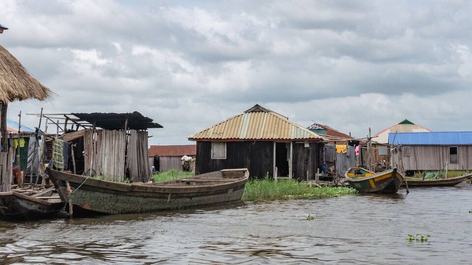 A riverside settlement with wooden houses and boats.
