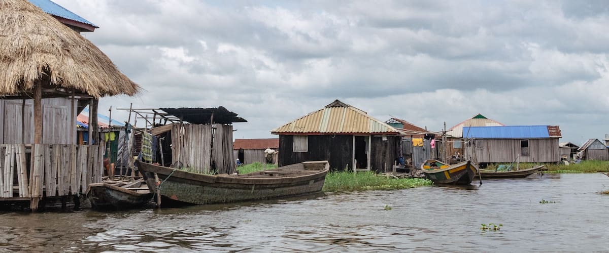 A riverside settlement with wooden houses and boats.