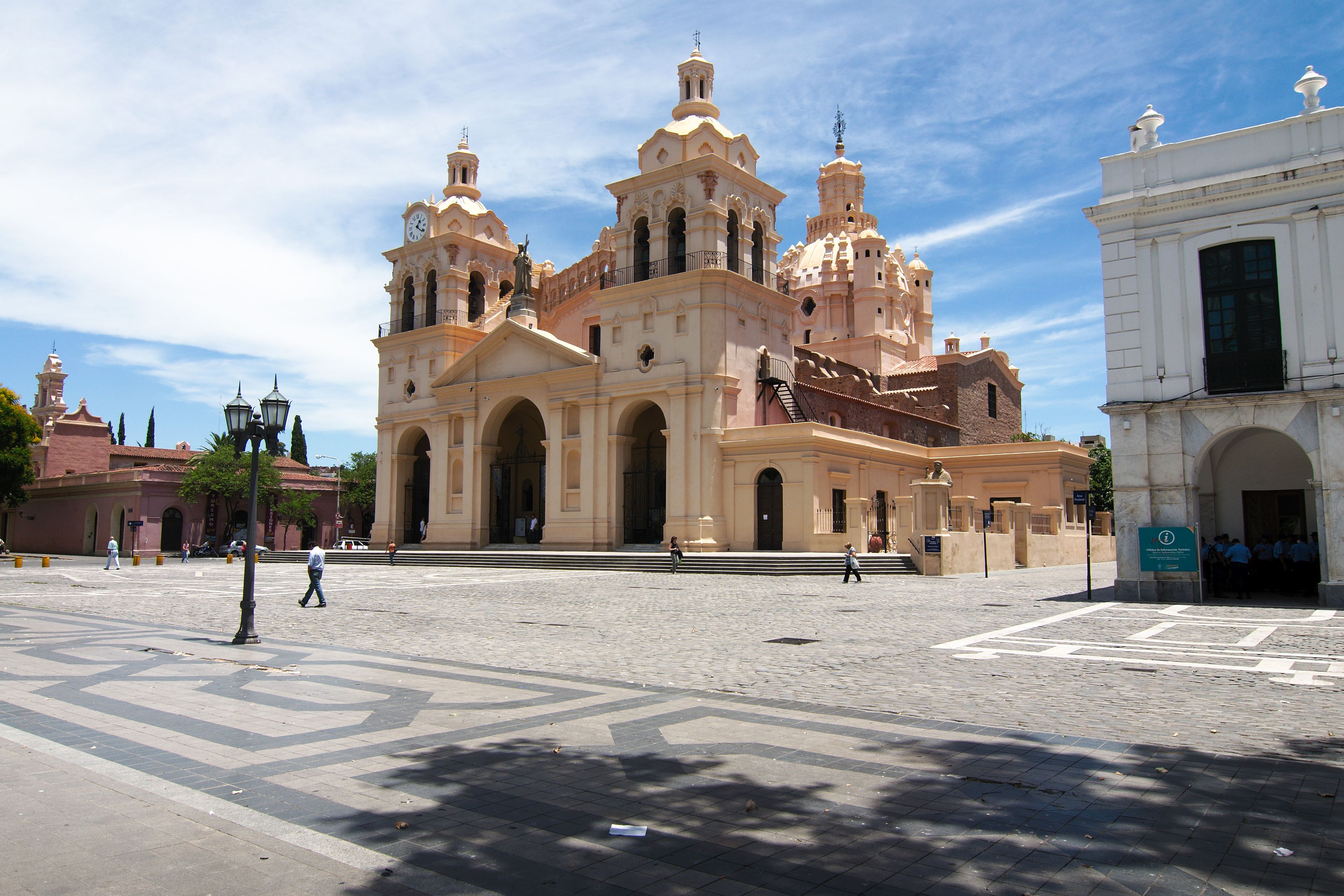 A historic cathedral with multiple towers and arches, a cobblestone plaza, and a clear blue sky.
