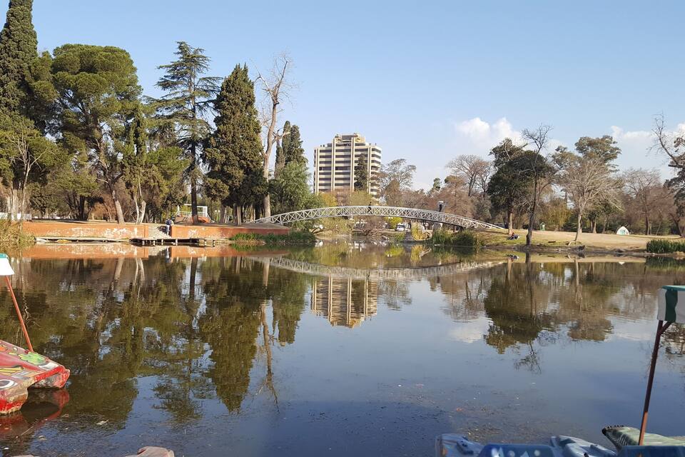 Un parque con un puente, un estanque y un edificio al fondo.