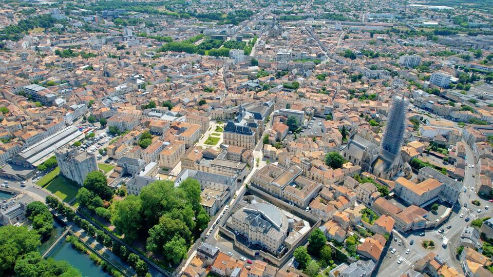 An aerial view of a densely built urban area with historic architecture, a prominent church, and a river.