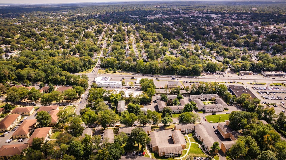 An aerial view of a residential area with houses, streets, and a large parking lot.