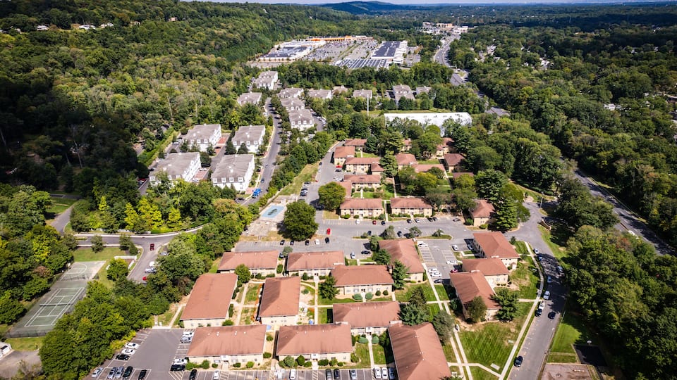An aerial view of a residential area with houses, roads, and a large parking lot.