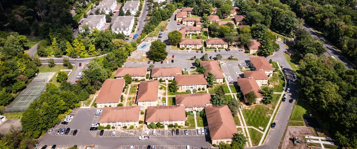 An aerial view of a residential area with houses, roads, and a large parking lot.