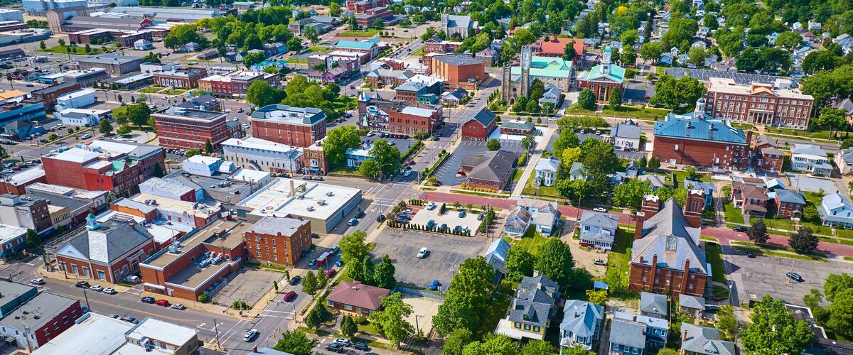 An aerial view of a town with historic buildings, a church, and a large parking lot.