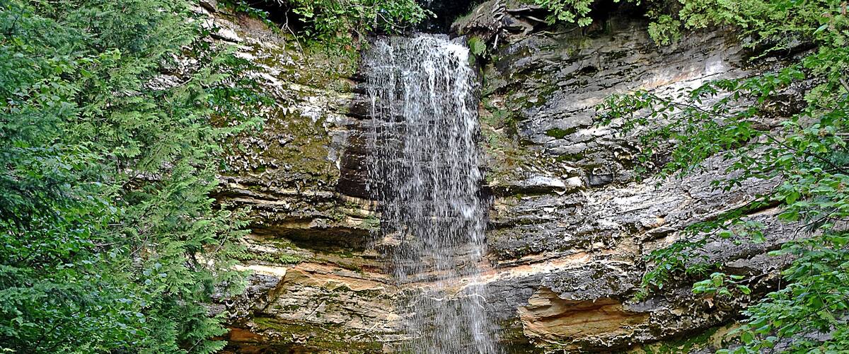 Munising Falls is a waterfall located in Munising in the westernmost portion of the Pictured Rocks National Lakeshore in Alger County. The falls drops about 50 feet over a sandstone cliff. With the exception of the spring thaw, the amount of water falling is relatively small. Wiki