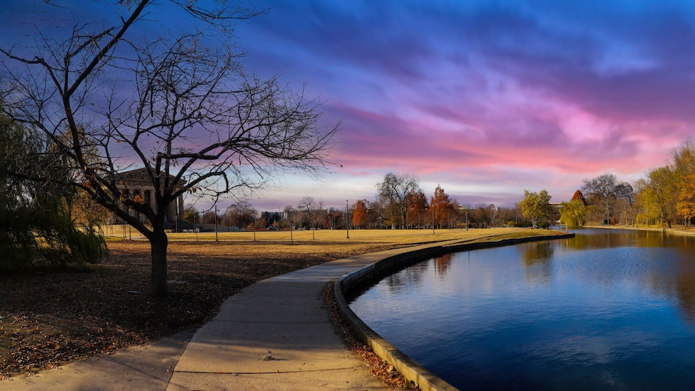 a stunning panoramic shot of the blue waters of the lake in the park surrounded by gorgeous autumn colored trees reflecting off the lake at sunset at Centennial Park in Nashville Tennessee USA