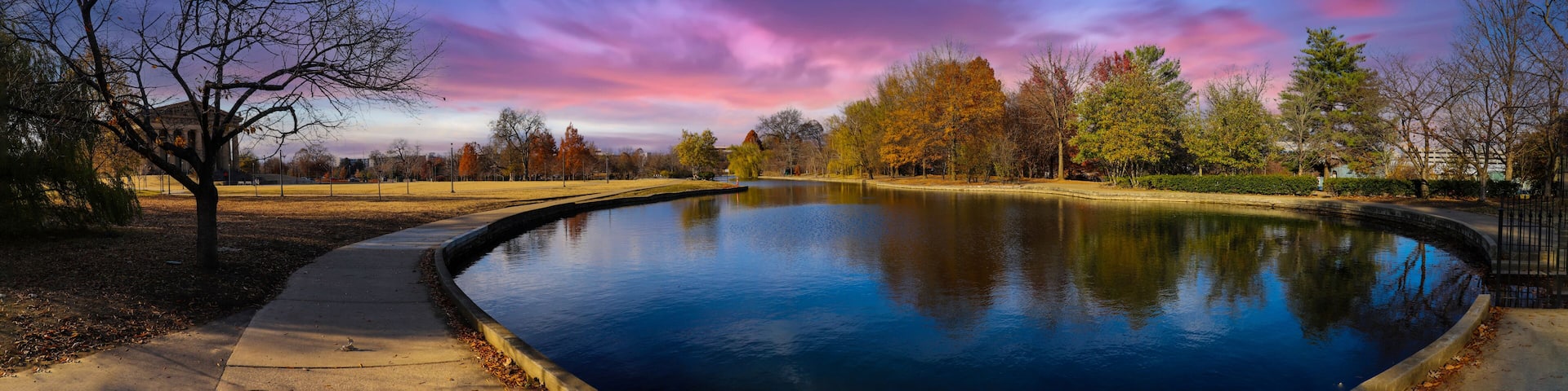 a stunning panoramic shot of the blue waters of the lake in the park surrounded by gorgeous autumn colored trees reflecting off the lake at sunset at Centennial Park in Nashville Tennessee USA
