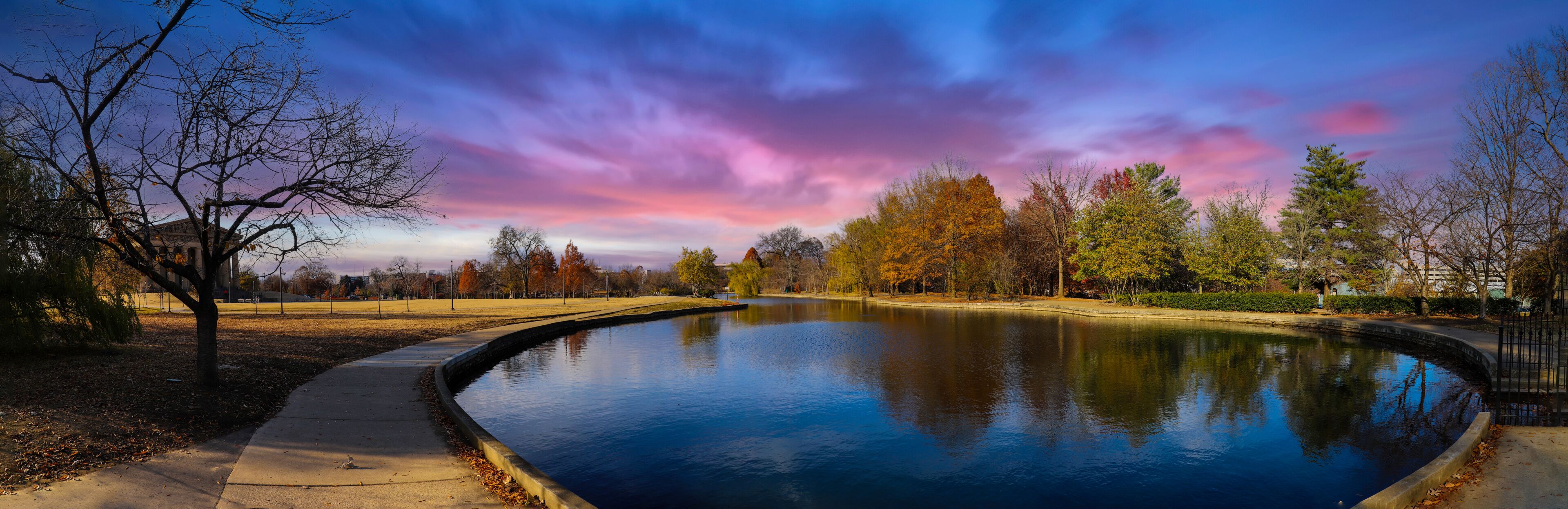 a stunning panoramic shot of the blue waters of the lake in the park surrounded by gorgeous autumn colored trees reflecting off the lake at sunset at Centennial Park in Nashville Tennessee USA