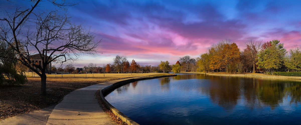 a stunning panoramic shot of the blue waters of the lake in the park surrounded by gorgeous autumn colored trees reflecting off the lake at sunset at Centennial Park in Nashville Tennessee USA