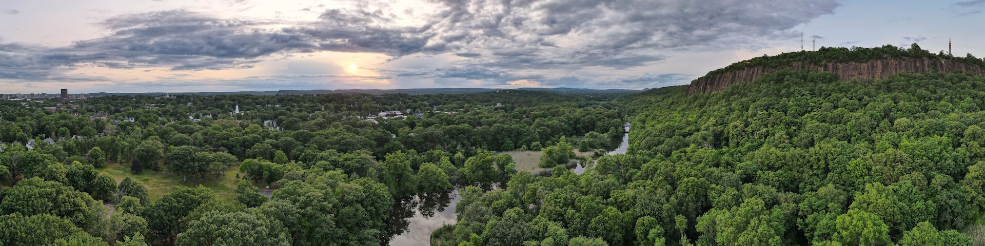 Aerial view of lush forest, river, cliff, and sky at East Rock Park, New Haven, Connecticut, United States.