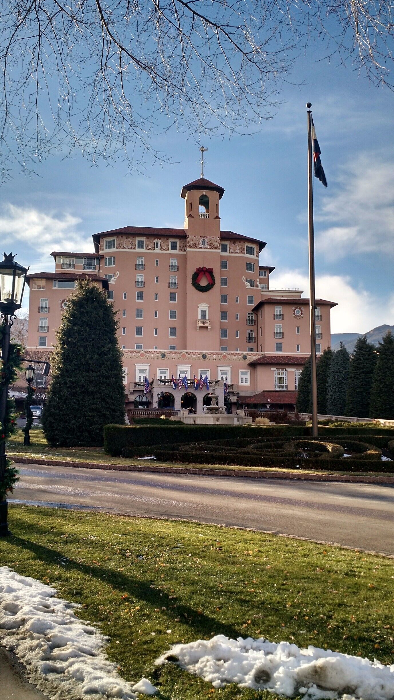 A large building with a tower, flags, and a wreath on the facade.