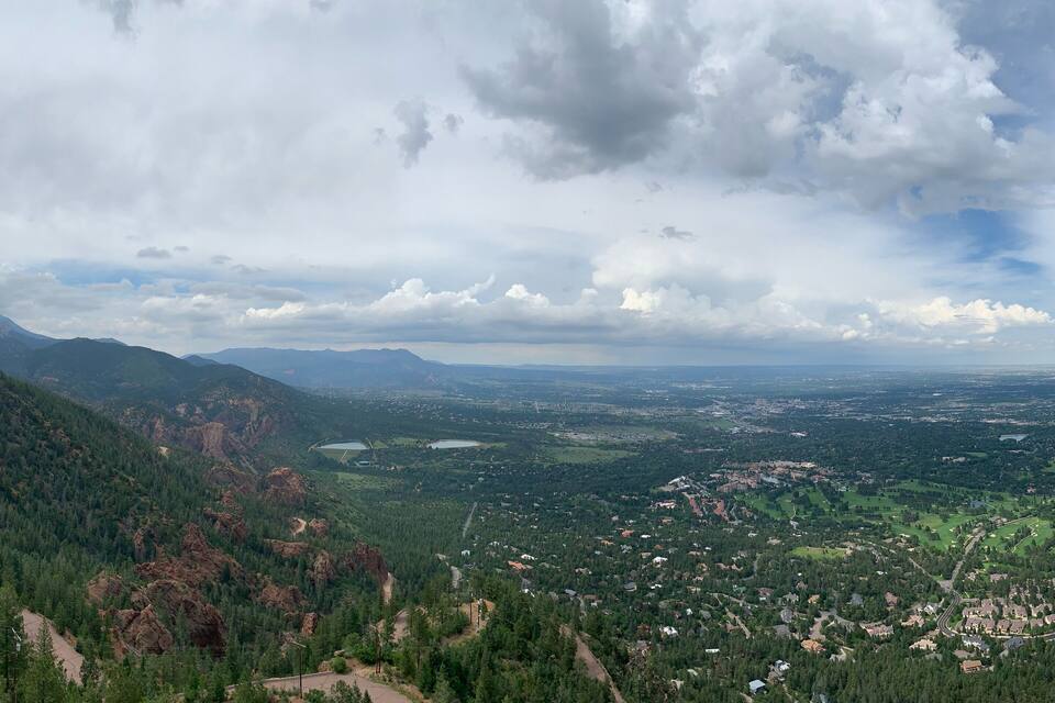 Eine gebirgige Landschaft mit einem Tal, einem See und verstreuten Häusern.