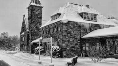 A historic stone building with a clock tower and a snow-covered roof.