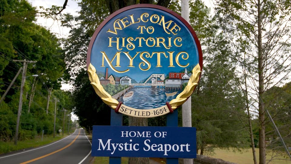 A welcome sign for Mystic Seaport, featuring a historic town illustration and a date of settlement.
