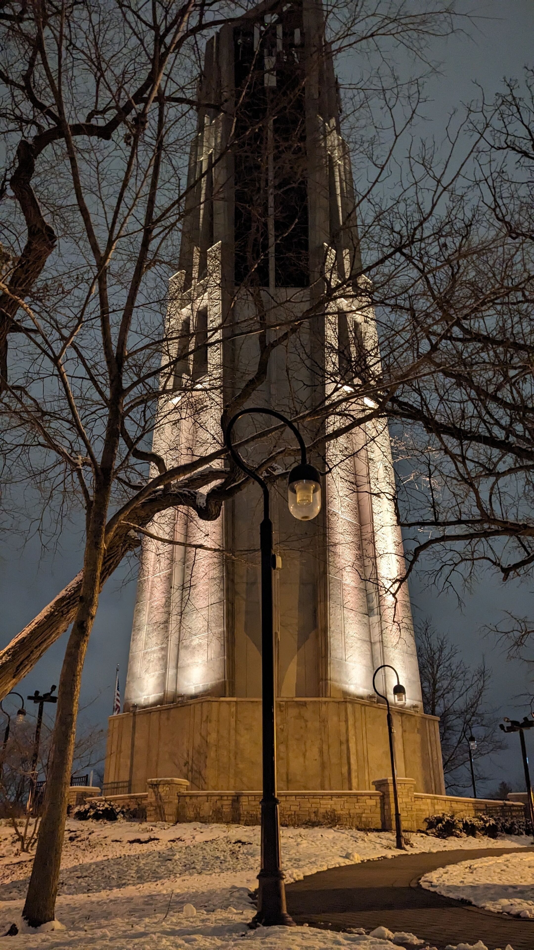 A snow-covered tower with a street lamp in front.