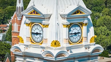 Une tour de l’horloge, surmontée de deux grandes horloges, entourée d’une architecture richement décorée et de verdure.