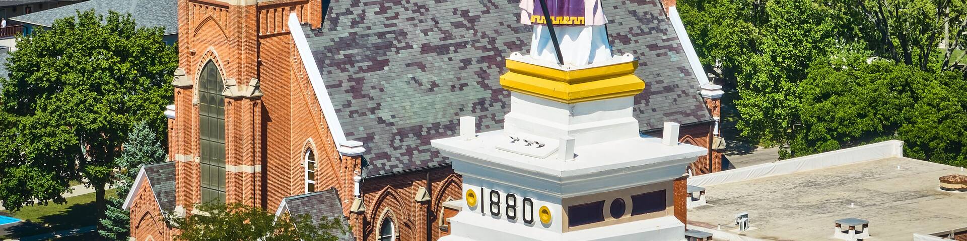 Aerial Detail of Statue on Top of Historic Courthouse and Church in Town