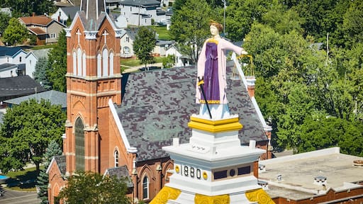 Aerial Detail of Statue on Top of Historic Courthouse and Church in Town