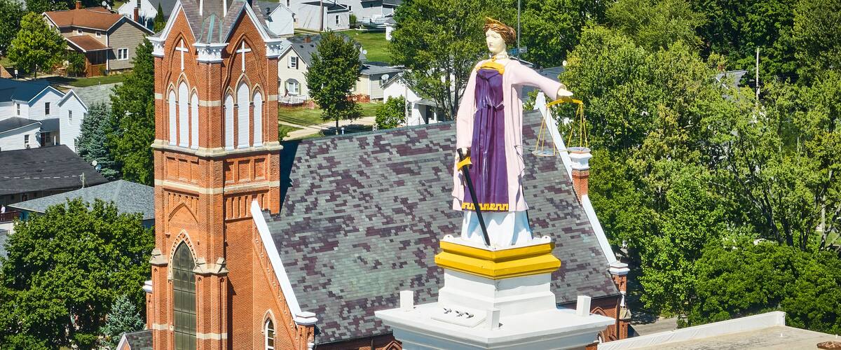 A church with a tall steeple and a statue on top.