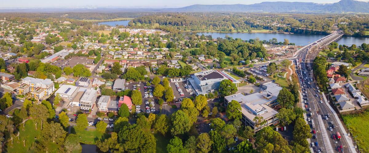 An aerial view of a town with a bridge, a lake, and surrounding greenery.