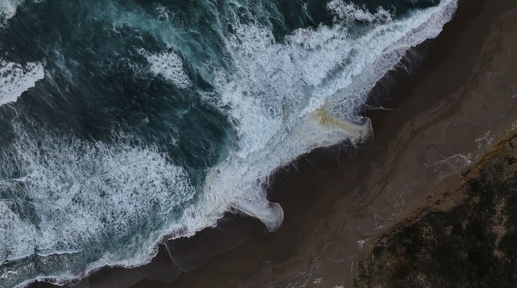 Aerial view of the dramatic meeting of dark, churning ocean waves and the sandy shore, a dance of power and tranquility, Point Reyes Station, California, United States.