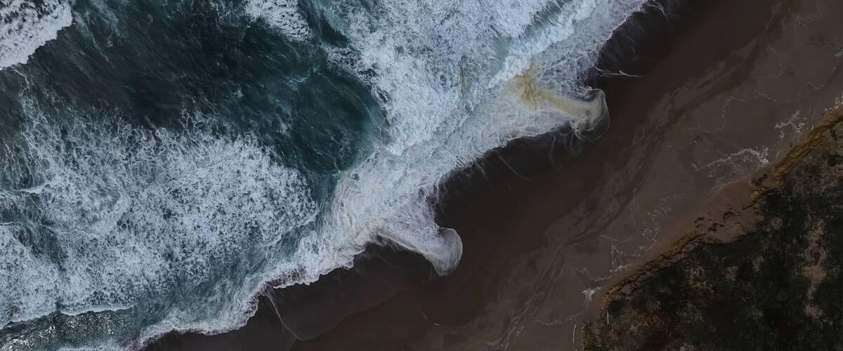Paisagem costeira com ondas quebrando na praia.