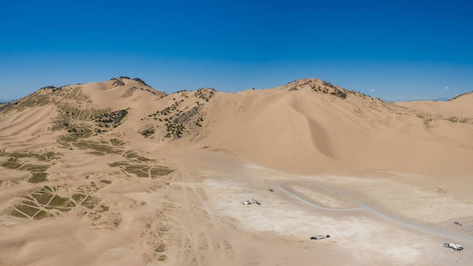 A vast desert landscape with sand dunes and winding roads.