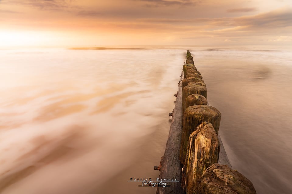 A long pier extending into calm waters during sunset.